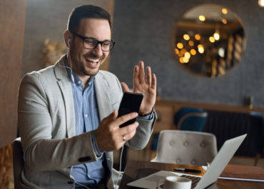 Happy Businessman Making A Video Call Over Smart Phone And Waving To Someone